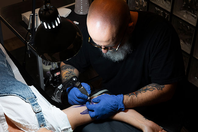 Tatuador realizando tatuaje hiperrealista